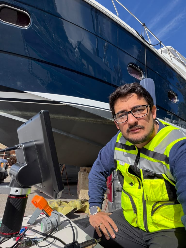 Marine technician working beside a dark blue yacht hull