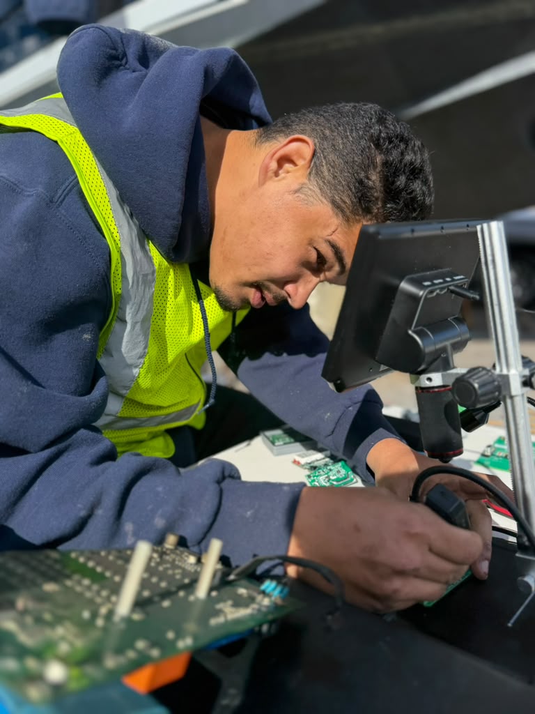 Technician repairing an electronic board under a digital microscope